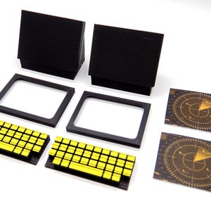 May include: An assortment of black and yellow game pieces. The set includes two black boxes, two black frames, two yellow and black keyboards, and two radar screen cards. The pieces are arranged on a white surface.