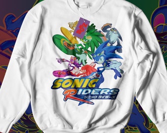 May include: White long-sleeve sweatshirt with a colorful graphic of Sonic the Hedgehog and his friends from the Sonic Riders video game. The graphic includes the text "Sonic Riders" and the Japanese text "ソニック ライダース".