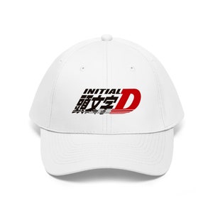 Puede incluir: Gorra de béisbol blanca con un logotipo Initial D negro y rojo. El logotipo presenta los caracteres japoneses para "Initial D" y una "D" roja con una franja de carreras blanca.