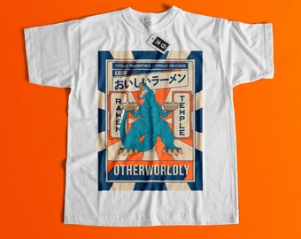 May include: White t-shirt with a graphic print of a blue monster holding two bowls of ramen. The graphic has the text "Kaiju" and "Oishii Ramen" in Japanese. The text "Ramen Temple" is on the right side of the graphic. The text "Otherworldly" is at the bottom of the graphic.