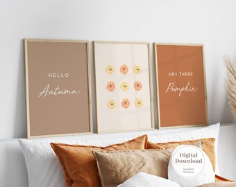 Könnte beinhalten: Drei gerahmte Wandbilder mit Herbstmotiven. Das linke Bild ist braun mit dem Text "HELLO Autumn". Das mittlere Bild ist cremefarben mit einem Raster aus neun kleinen Kürbissen. Das rechte Bild ist orange mit dem Text "HEY THERE Pumpkin".