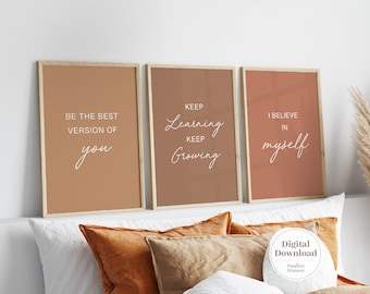 Peut inclure: Trois affiches murales rectangulaires dans des cadres en bois clair avec du texte de motivation en blanc. L'affiche de gauche indique BE THE BEST VERSION OF you, celle du centre KEEP Learning KEEP Growing, et celle de droite I BELIEVE IN myself.