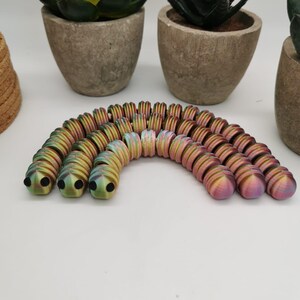 Könnte beinhalten: Ein Satz bunter Metallperlen, die in Regenbogenform angeordnet sind. Die Perlen sind schillernd und haben eine strukturierte Oberfläche.