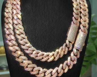 May include: A rose gold-toned cuban link chain necklace featuring two rows of interlocking links entirely encrusted with small, clear, reflective stones. The necklace includes a rectangular box clasp closure also covered in stones.