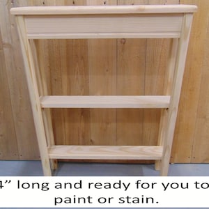 May include: A 24-inch long unfinished wooden shelf unit with three shelves. The shelf unit is ready to be painted or stained.