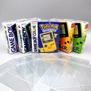 Può includere: Quattro console per videogiochi portatili Game Boy Color nella loro confezione originale. Le console sono blu, verdi, gialle e verdi. La console gialla è una edizione speciale Pokemon Game Boy Color. Le console sono su una superficie bianca con buste di plastica trasparente.
