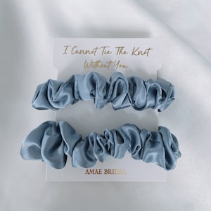 Może przedstawiać: Dwa jasnoniebieskie gumki do włosów z satyny na białej kartce z tekstem "I Cannot Tie The Knot Without You" i "AMAE BRIDAL".