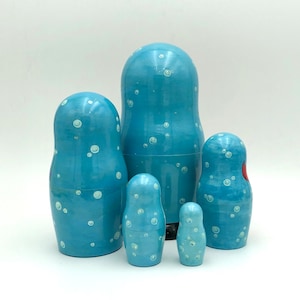 K&ouml;nnte beinhalten: Ein Satz von f&uuml;nf blauen und wei&szlig;en Nistpuppen, oder Matroschka-Puppen, mit einem wei&szlig;en Tupfenmuster. Die gr&ouml;&szlig;te Puppe ist die gr&ouml;&szlig;te und die kleinste Puppe ist die kleinste.