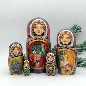 May include: Set of five traditional Russian nesting dolls, or matryoshka dolls, painted with a winter holiday theme. The largest doll depicts a woman in a purple dress and white fur trim, holding a red and gold Christmas tree ornament. The other dolls depict a man in a red and gold suit, a woman in a red dress, a woman in a white dress, and a woman in a blue dress.