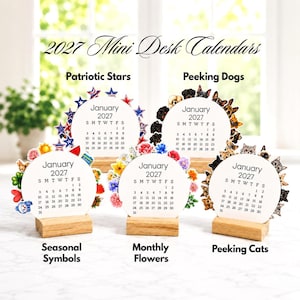 May include: Five 2027 mini desk calendars with circular pages set in light wood blocks. Designs include Patriotic Stars, Peeking Dogs, Seasonal Symbols, Monthly Flowers, and Peeking Cats. Each calendar displays the month of January 2027.
