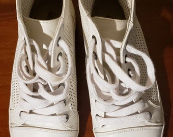 May include: A pair of white high-top sneakers with a perforated design and white laces.