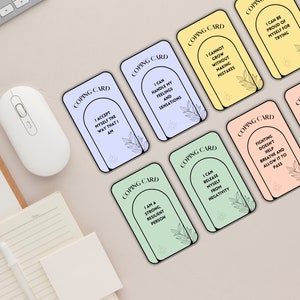 Puede incluir: Un juego de diez cartas de afrontamiento con afirmaciones positivas impresas en ellas. Cada carta presenta un color diferente y una ilustraci&oacute;n simple de un arco con hojas. El texto en las cartas incluye frases como "Puedo manejar mis sentimientos y sensaciones" y "Soy una persona fuerte y resiliente".