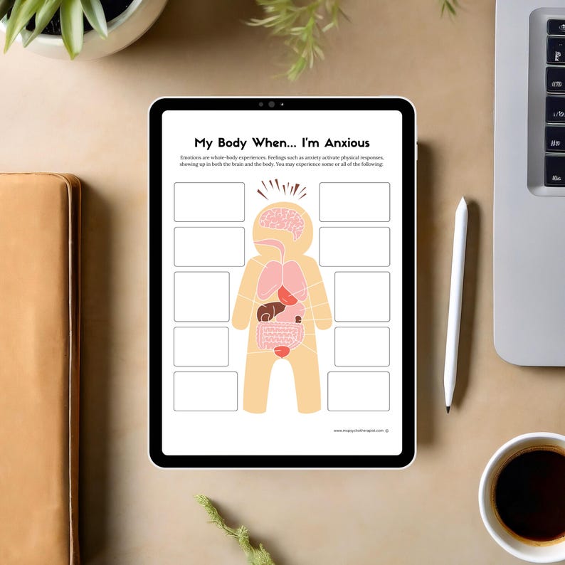 May include: A digital tablet displays a worksheet titled "My Body When... I'm Anxious." The worksheet features a diagram of a human body with labeled internal organs and blank spaces for notes. The tablet is on a beige surface.