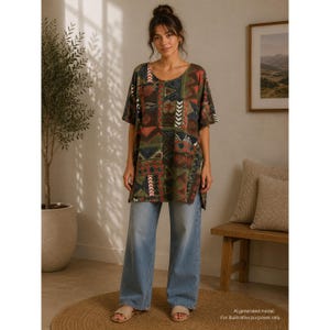 May include: A short-sleeved tunic featuring a multi-colored geometric patchwork pattern in shades of green, red, and blue, paired with light blue wide-leg denim jeans. The tunic has a round neckline and side slits at the hemline.