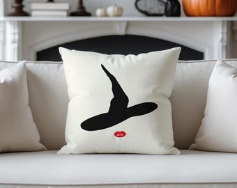 May include: A white decorative pillow featuring a black witch hat and red lips design. The pillow is on a white sofa. The text "Wicked Cat" is at the bottom left corner.