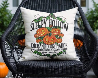 Può includere: Un cuscino quadrato bianco con un design a tema Halloween. Presenta lanterne di zucca arancioni e il testo "Sleepy Hollow Enchanted Orchards". Il cuscino è su una sedia di vimini nera. Il testo "Wicked Cat" è in basso a sinistra.