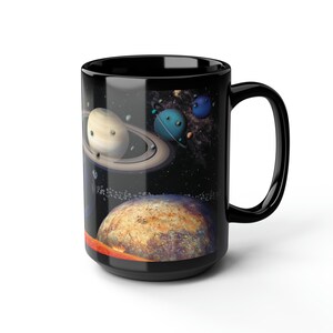 Op de afbeelding: Zwarte keramische mok met een kleurrijk beeld van planeten en sterren in de ruimte. De mok heeft een groot handvat.