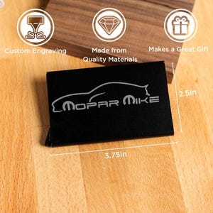 May include: Black business card holder with the text "Mopar Mike" and a car silhouette. The holder measures 3.75 inches long and 2.5 inches high. The image also includes icons that say "Custom Engraving", "Made from Quality Materials", and "Makes a Great Gift".