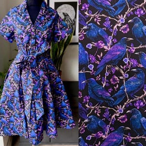 Könnte beinhalten: Ein kurzärmeliges Kleid mit Kragen und Bindegürtel. Das Kleid hat ein lebendiges Muster aus blauen und violetten Vögeln auf schwarzem Hintergrund. Der Stoff erscheint auch auf einem separaten Panel.