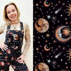 Op de afbeelding: Een vrouw draagt een zwarte overall met een hemelse print met manen, sterren en zonnen. De print is in tinten goud, oranje en wit op een zwarte achtergrond.