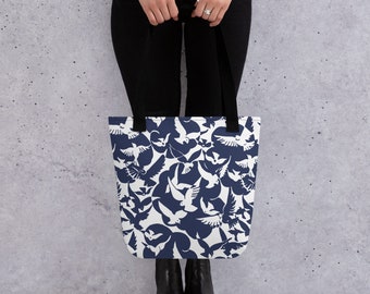 May include: A navy blue tote bag with a white silhouette pattern of flying birds. The bag has two black handles.
