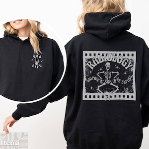 May include: Black hoodie with a white graphic on the back that says "Radiology" with a skeleton and the text "You Pose We Expose". The front of the hoodie has a small white graphic that says "Rad Life" with a rock and roll hand symbol.