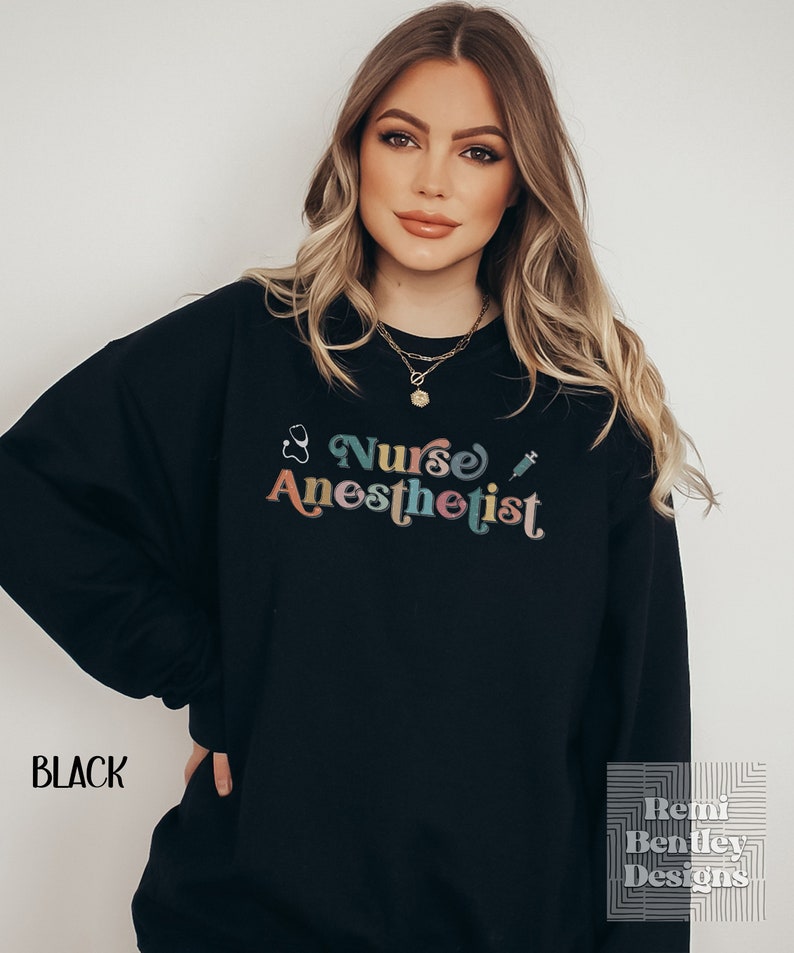 May include: Black sweatshirt with a colorful retro graphic that says "Nurse Anesthetist" with a stethoscope and syringe.