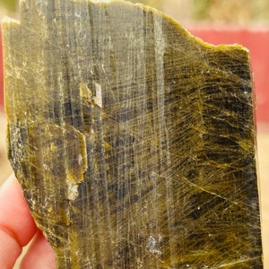 May include: A large, flat piece of green and brown mica with a striated texture. The mica is translucent and has a slight sheen.