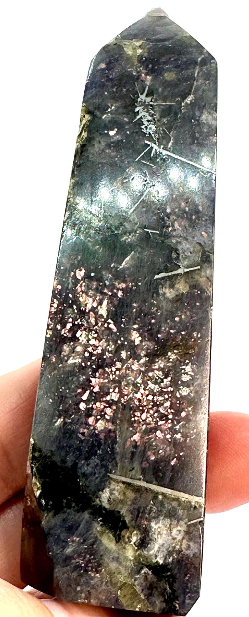 May include: A tall, rectangular crystal obelisk with a polished surface. The stone features a dark, mottled base color with areas of pink and white speckling. Thin, white lines run through the stone.