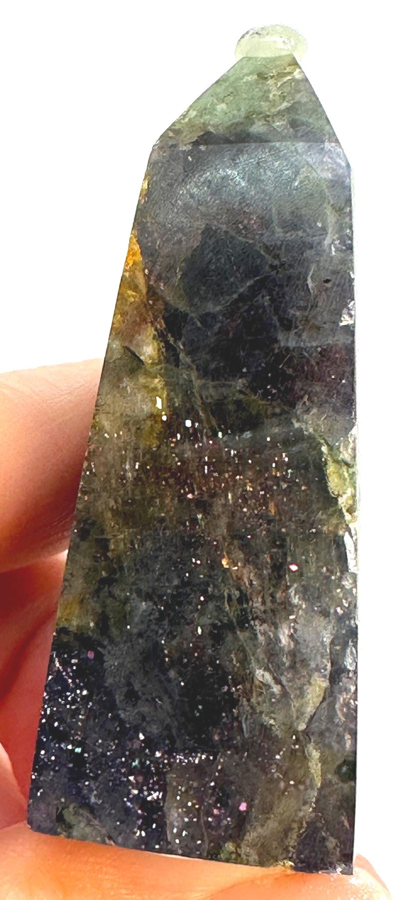 May include: A polished, triangular-shaped gemstone obelisk. The stone features a dark, mottled appearance with shades of green, black, and gold. Tiny, sparkling inclusions are scattered throughout the surface, adding a glittery effect.