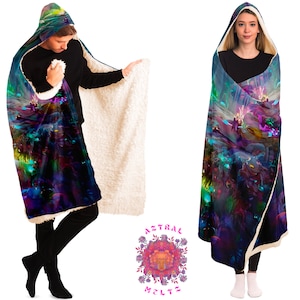 K&ouml;nnte beinhalten: Eine Kapuzendecke mit einem farbenfrohen, abstrakten Design mit wirbelnden Farben und Formen. Die Decke ist aus weichem, pl&uuml;schem Stoff gefertigt und hat ein Sherpa-Futter. Die Decke wird von zwei Personen getragen, eine steht, die andere sitzt.