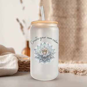 May include: Frosted glass tumbler with a bamboo lid and a silver straw. The tumbler features a blue and white floral design and the text "Create your own calm". A stylish and reusable drinkware item.