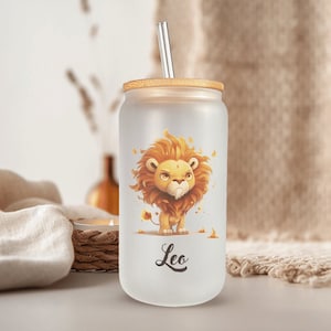 May include: Frosted glass tumbler with a bamboo lid and a stainless steel straw. The tumbler features a cartoon lion illustration with the word "Leo" below. The lion is depicted in shades of orange and yellow.