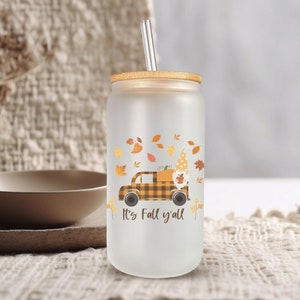 May include: Frosted glass tumbler with a bamboo lid and a silver straw. The tumbler features a fall-themed design with a plaid truck, a gnome, and autumn leaves. The text "It's Fall y'all" is printed on the front.