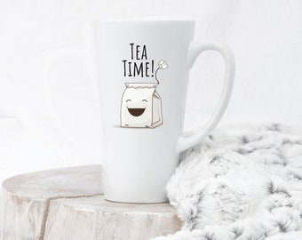 May include: White ceramic latte mug with a black and brown illustration of a tea bag with a smiling face and the text "TEA TIME!" printed on the front.
