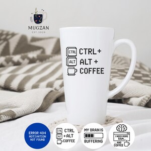 Könnte beinhalten: Hohe, weiße Keramik-Kaffeetasse mit dem Text "CTRL + ALT + COFFEE" in Schwarz und weiteren computerbezogenen Grafiken. Die Tasse trägt auch den Text "ERROR 404 MOTIVATION NOT FOUND".