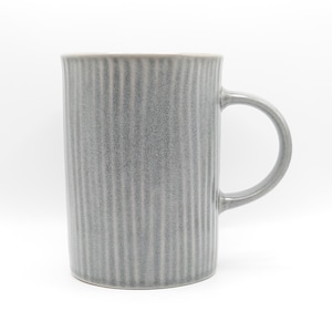 May include: A gray ceramic mug with vertical ribbed detailing. The mug has a rounded handle and a cylindrical shape. The color is a muted gray, and the mug appears to be made of stoneware or a similar material.