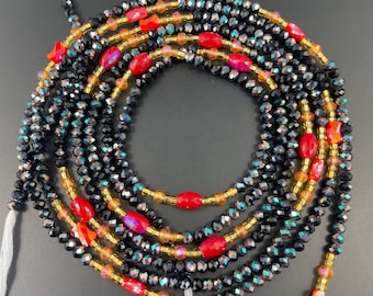 May include: A multi-strand waist bead necklace with black, gold, and red beads. The beads are arranged in a pattern of black, gold, and red beads.