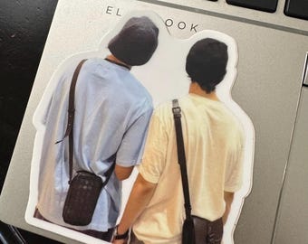 May include: Two people wearing hats and carrying black crossbody bags. The person on the left is wearing a light blue shirt and the person on the right is wearing a light yellow shirt.