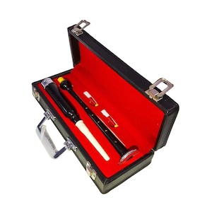 Puede incluir: Un juego de gaita negra en un estuche negro con interior de terciopelo rojo. El juego incluye un puntero negro, un soplete negro y dos lengüetas. El estuche tiene un asa y cierres plateados.