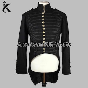Puede incluir: Chaqueta negra de estilo militar con botones dorados y costuras decorativas. La chaqueta tiene cuello alto y mangas largas. El texto "American Kilt Crafts" está impreso en la parte delantera.