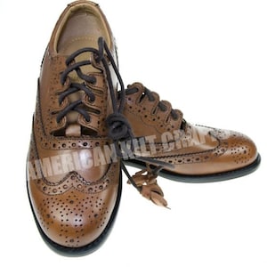 May include: A pair of brown leather brogue shoes with decorative stitching and laces. The shoes have a wingtip design and are made of a high-quality leather.