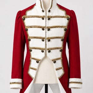 May include: A red and white military-style jacket featuring a high collar, long sleeves with white cuffs, and a front panel decorated with horizontal gold braided trim and metallic buttons. The garment has a structured fit and a split tail design.