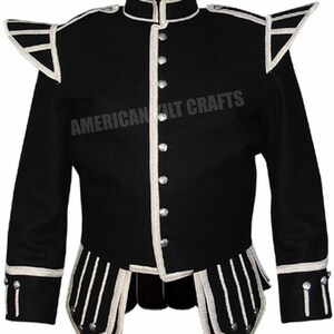 May include: Black kilt jacket with white piping and buttons. The jacket has a stand-up collar and a double-breasted closure. The jacket is trimmed with white piping and buttons. The jacket has a  "AMERICAN KILTCRAFTS" label on the front.
