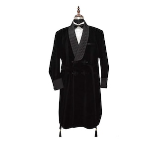 May include: A black velvet smoking jacket with a quilted shawl collar and cuffs. The jacket features a double-breasted design with decorative buttons and a matching belt. Black tassels hang from the bottom hem. A white dress shirt and bow tie are visible.