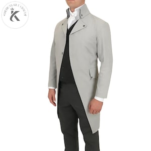May include: A light grey, long coat with a high collar and a single-button closure. The coat has a tailored fit and is worn over a black waistcoat and dark grey trousers. The coat features an asymmetrical design, suitable for formal occasions.