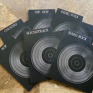 May include: A set of six black rectangular vinyl record dividers with tabs labeled Country, Hip-Hop, Indie/Folk, Soundtrack, Pop, and Hard Rock. Each divider features a circular graphic design resembling a vinyl record with concentric rings.