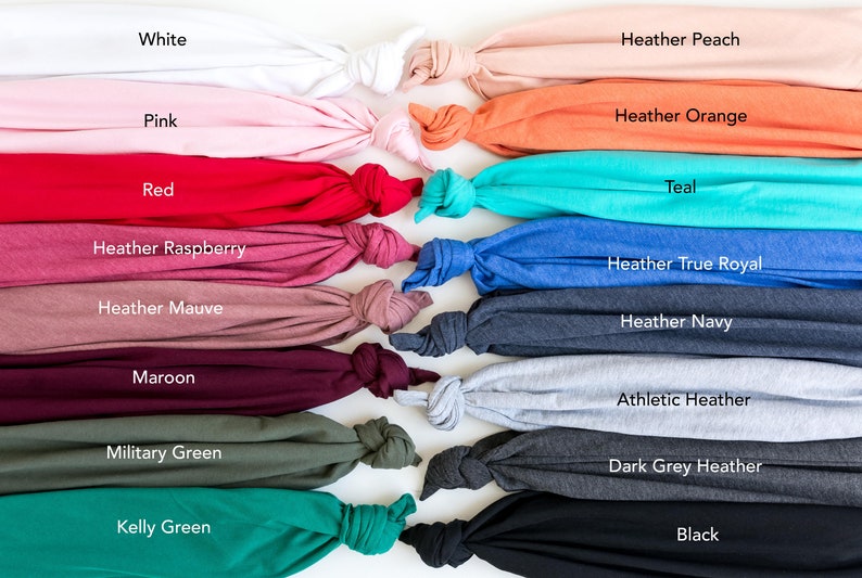 May include: An assortment of folded t-shirts in a range of colours, such as white, pink, red, and black. Other colours include heather peach, orange, teal, and true royal. Each shirt is labelled with its colour name.