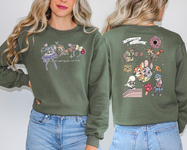 May include: An olive green sweatshirt with cartoon character designs on the front and back. The front has character-themed accessories and the text "Can be anything you wish to be." The back features character illustrations and the text "The Big Donut."