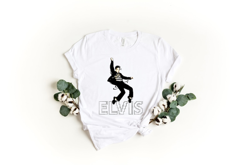 K&ouml;nnte beinhalten: Wei&szlig;es T-Shirt mit einem Schwarzwei&szlig;bild von Elvis Presley in einer Sprungpose. Das Wort "ELVIS" ist in Schwarz mit wei&szlig;en Punkten unter dem Bild gedruckt.